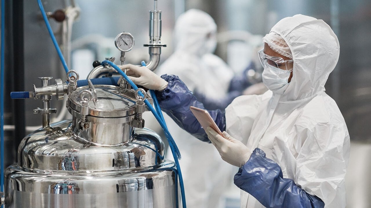 Portrait of female worker wearing protective suit while operating equipment at modern chemical plant, copy space